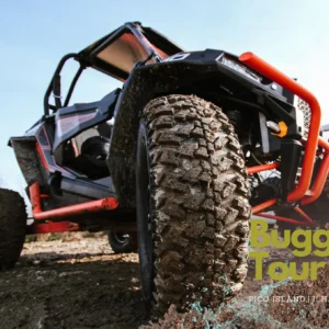 Off-road buggy with large, muddy tires positioned on uneven terrain.