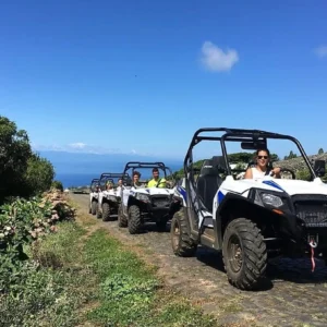 Line of off-road buggies driving on a path on Terceira Island with a clear blue sky.