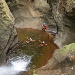 Group of individuals participating in canyoning in a rocky area with water.