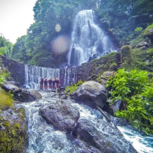 Group of individuals participating in canyoning near a waterfall in Sao Miguel, Azores.