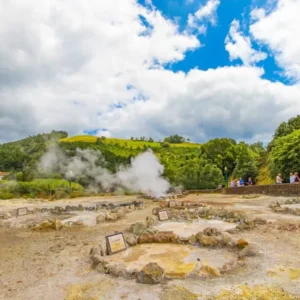 Geothermal area in Furnas with steam rising from hot springs and rocky formations.