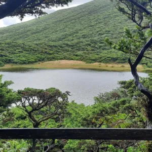 A serene view of a lake surrounded by lush greenery and hills in Lagoinha.