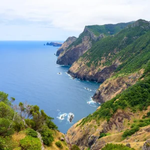 Coastal landscape featuring cliffs and ocean at Boca Risco, with greenery on the slopes.