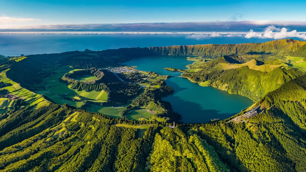 Aerial view of Sete Cidades, a volcanic crater lake in the Azores with green hills and blue water.