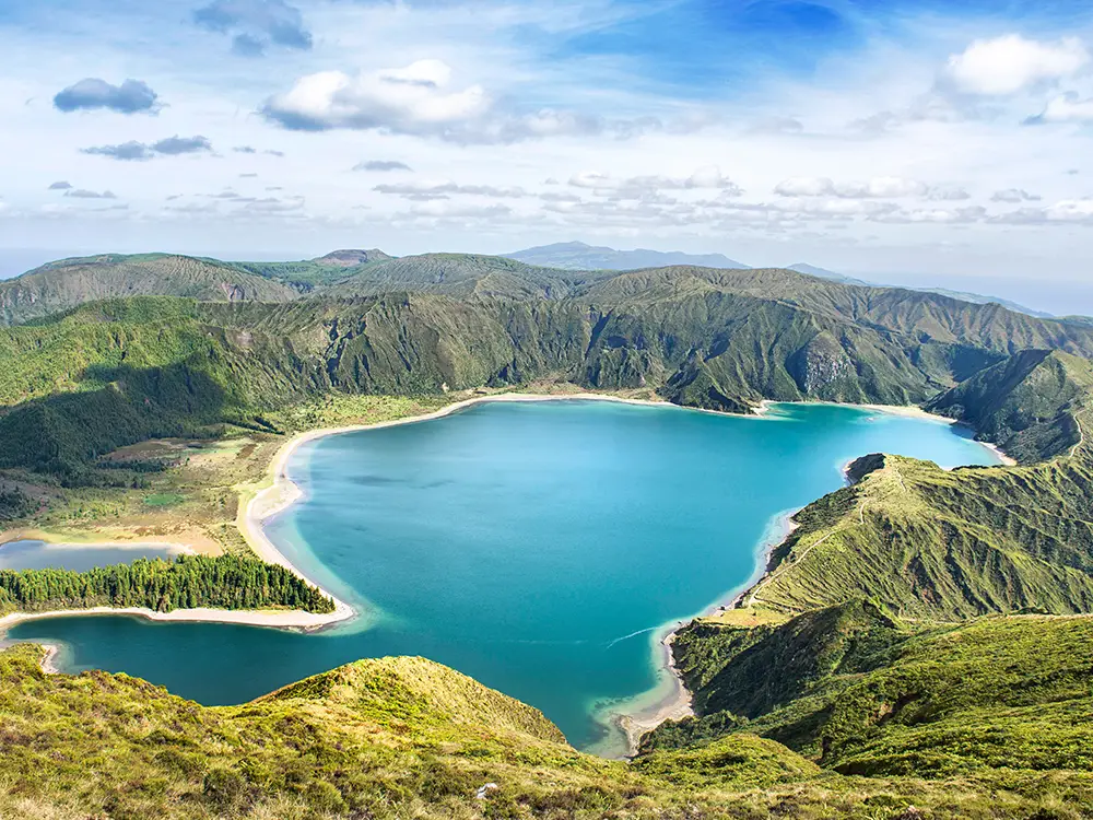 Aerial view of Lagoa do Fogo, a blue lake surrounded by green hills in the Azores.