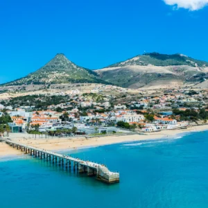 Aerial view of Porto Santo Island featuring a beach, pier, and mountainous landscape.