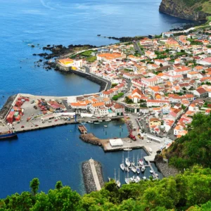 Aerial view of a coastal town featuring a harbor, colorful buildings, and boats in the water.