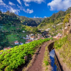 A walking path along green hills with a view of a village in the distance in Morocco.
